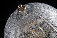 Detailansicht einer Spitzengravur auf dem Glasschirm einer dekorativen Lampe.