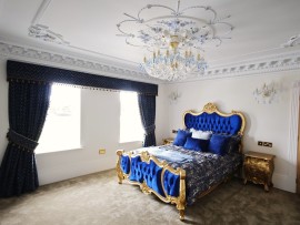 Die Version des Kronleuchters mit 18 Glühbirnen passt gut zum blauen Doppelbett im Schlafzimmer.