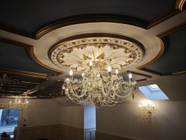 Luxuriös eingerichtete, niedrige Räume im Dachgeschoss eines Hauses mit farbenfrohen Kristallkronleuchtern