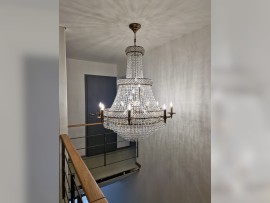 Der Kronleuchter passt gut in ein minimalistisches Interieur mit Holzgeländer.